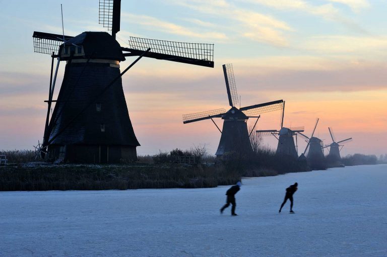 Molens en schaatsers bij Kinderdijk.